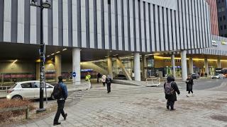 Isonrakennuksen kupeessa kävelee ihmisiä. 