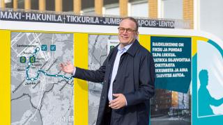 Kaupunginjohtaja ratikan kartan edessä.