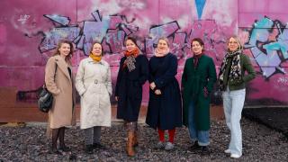 Kuusi henkilöä seisoo graffitin edessä