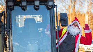 Joulupukki vilkuttaa kaivinkoneesta.
